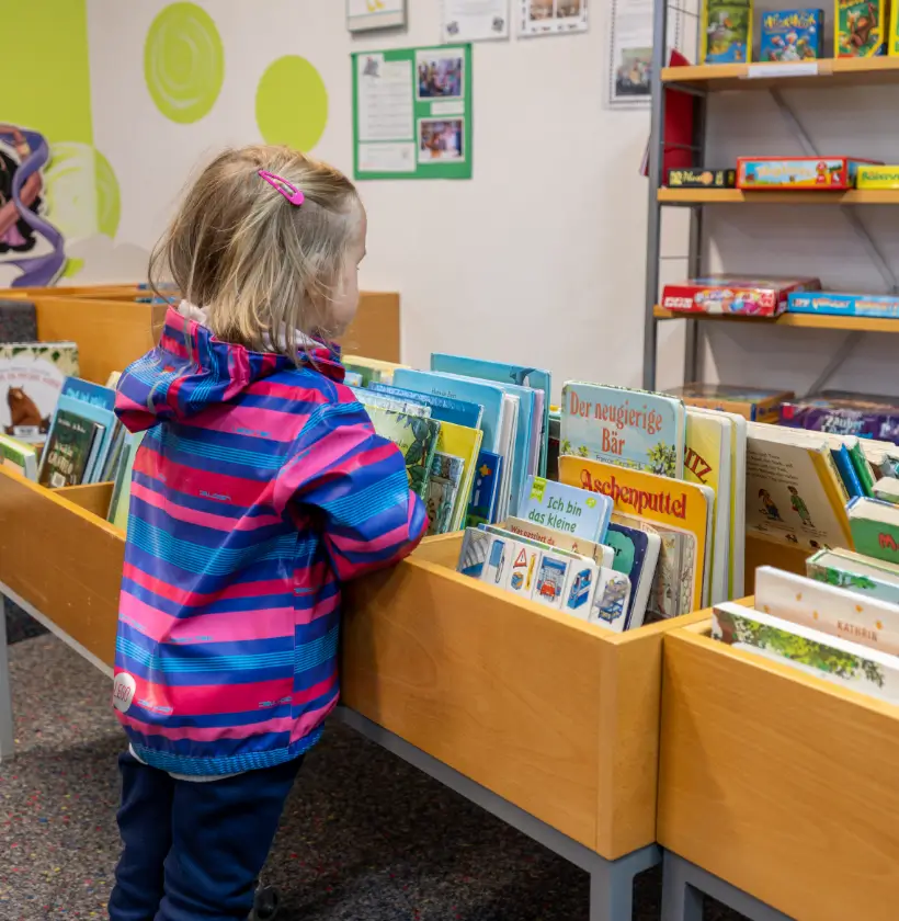 Kind steht vor Bücherkisten